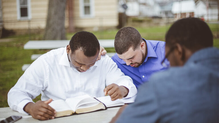 group of men reading the bible and praying